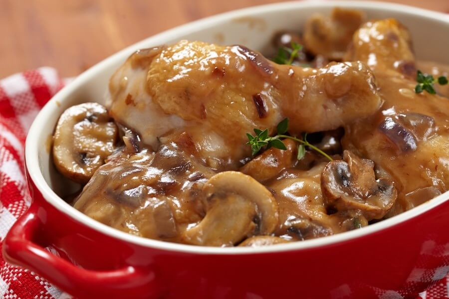 A delicious red handled bowl filled with delicious mushroom wine sauce slow cooked chicken!