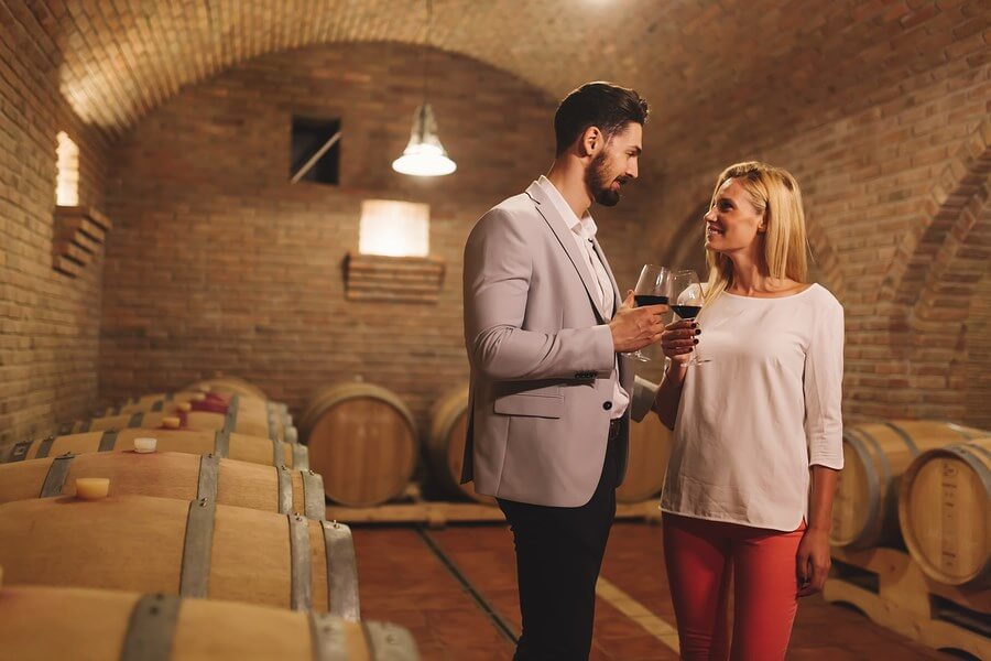 A pair of wine drinkers enjoy their wine tasting experience within a beautiful wine cellar!
