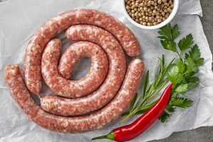 Sumptuous, Delicious Italian pork sausages, with a bowl a coriander seeds, parsley, and red chili pepper